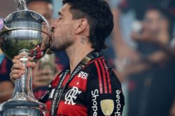 Arrascaeta em campo com a camisa do Flamengo, sorrindo e celebrando, representando sua performance no ano em que foi finalista do Prêmio Rei da América.
