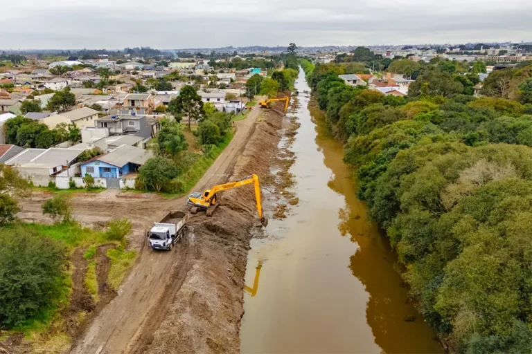 Maquinários de Pinhais e Piraquara atuam no leito do Rio Iraí para prevenir inundações e melhorar a drenagem urbana nas divisas municipais